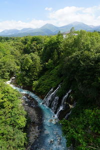 Scenic view of waterfall in forest against sky