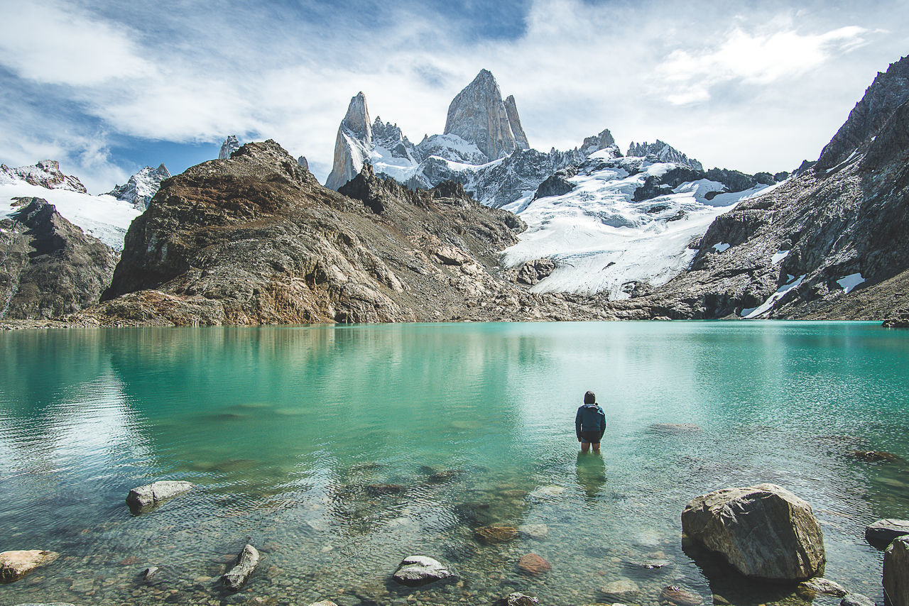 water, beauty in nature, scenics - nature, mountain, real people, leisure activity, solid, rock, lake, rock - object, tranquil scene, sky, mountain range, nature, non-urban scene, lifestyles, winter, tranquility, one person, outdoors, snowcapped mountain, turquoise colored