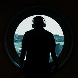 Rear view of silhouette man looking through window