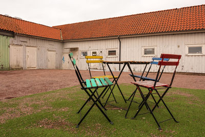 Multi colored chairs outside house on field against sky