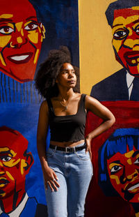 Portrait of woman standing against graffiti wall