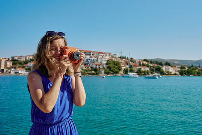 Side view of woman photographing against sea