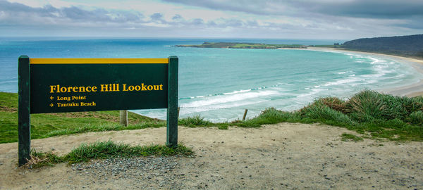 Information sign on beach against sky