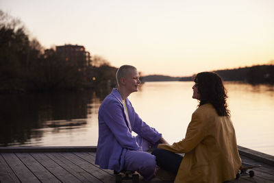 Young female gay couple sitting and looking at each other at river