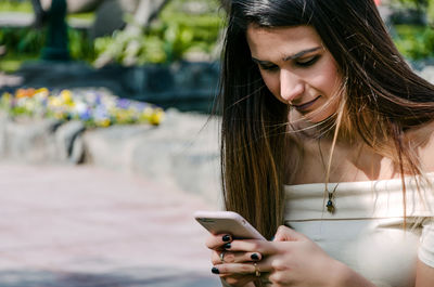 Smiling young woman using smart phone outdoors