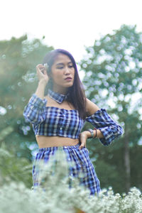 Young woman standing against plants