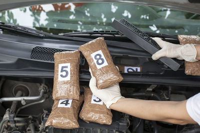 Cropped hand holding cocaine parcels in car