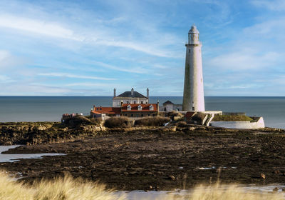 Lighthouse by sea against sky