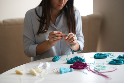 Woman embroiders with beads and makes brushes, handwork concept and housewife hobby