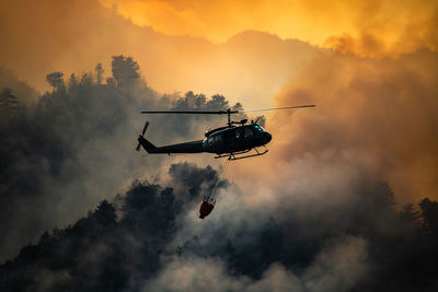 Low angle view of silhouette helicopter against sky during sunset