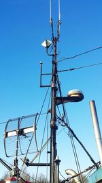 Low angle view of electricity pylon against clear blue sky