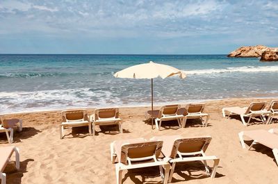 Deck chairs on beach against sky