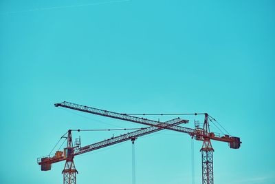 Low angle view of crane against clear blue sky