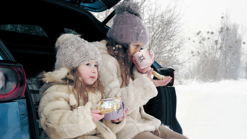 Winter tea picnic. little girl, dressed in warm winter clothes, are having tasty snack