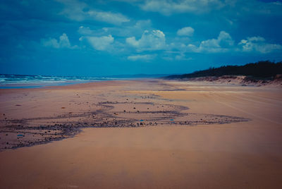 Scenic view of beach against cloudy sky