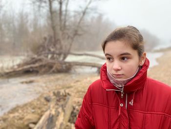 Girl looking away while standing outdoors during winter