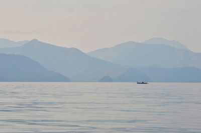 Scenic view of sea by mountains against sky