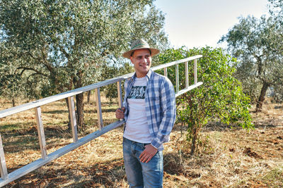 Portrait of young man standing against trees