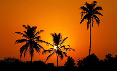 Silhouette palm trees against romantic sky at sunset