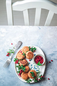 Breakfast set. russian cheese cakes on a craft ceramic plate with lingonberry over a blue background