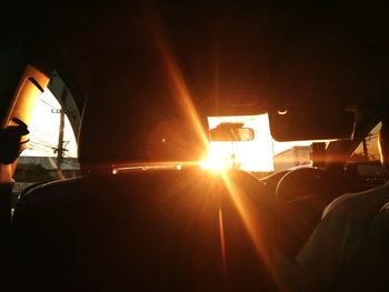 People in illuminated bus against bright sun