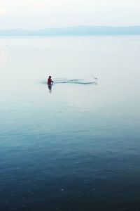 Distant view of fisherman fishing in lake