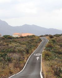 Road leading towards mountain range against sky