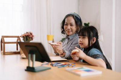 Grandmother teaching granddaughter at home