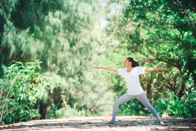 Full length of young woman practicing yoga in warrior position at park