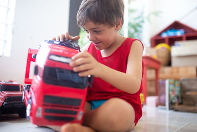 Boy playing with toy car while sitting on floor