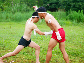 Shirtless young men practicing martial arts on field