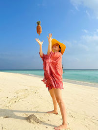 Full length of woman at beach with pineapple 