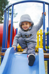 Smiling cute boy playing on slide at playground