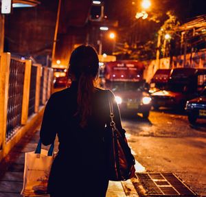 Rear view of woman walking on street at night