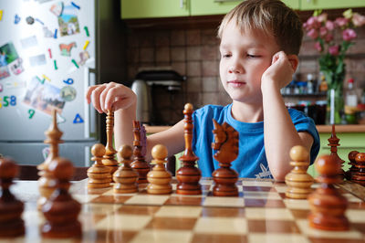 Portrait of boy playing chess at home