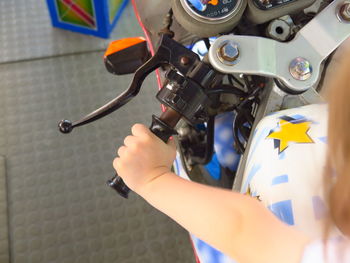 Cropped hand of girl sitting on motorcycle