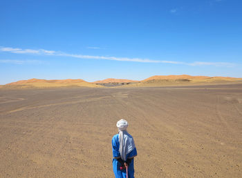 Rear view of man wearing hat on land against sky