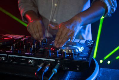 Midsection of man operating sound mixer at nightclub