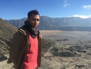 Portrait of young man standing against mountains