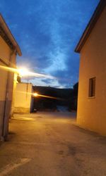 Road leading towards houses against blue sky