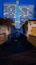 Illuminated street amidst buildings in city at night