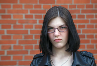 Portrait of a beautiful young woman against brick wall