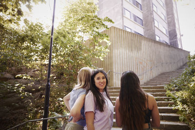 Three young female friends standing together and talking