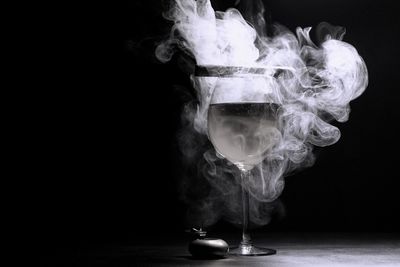 Wineglass amidst smoke against black background