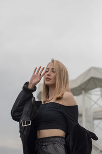 Beautiful young woman standing against sky