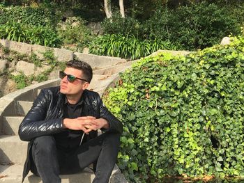 Mid adult man wearing sunglasses sitting on steps by plants