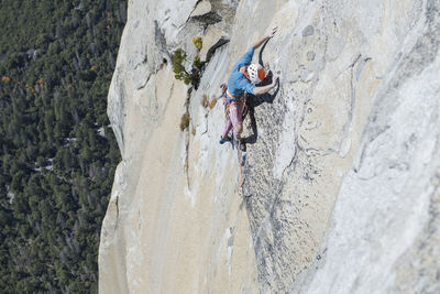 Climber looking down at his feet high up on el capitan exposed