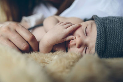 Cropped image of mother with sleeping daughter on bed at home