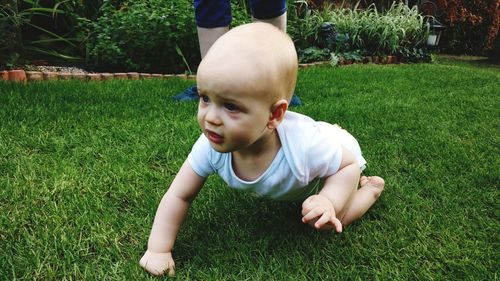 Cute baby boy crawling on grassy field in park