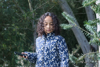 Portrait of young woman standing against plants